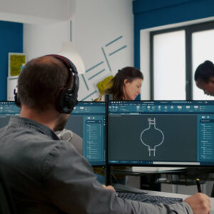 Engenheiro focado colocando fones de ouvido trabalhando com programa técnico cad verificando o protótipo de engrenagens