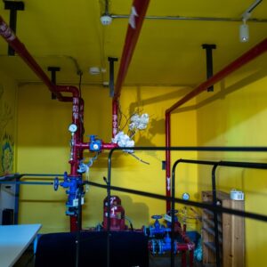 Uma Sala Com Paredes Amarelas E Tubos Vermelhos C80fSAOkEqE