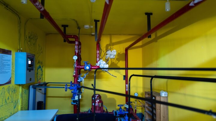 Uma Sala Com Paredes Amarelas E Tubos Vermelhos C80fSAOkEqE