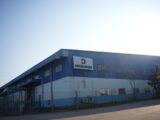 Predio Industrial Azul Com Logotipo Da Empresa Sob Ceu Limpo fb2leZe8xfQ