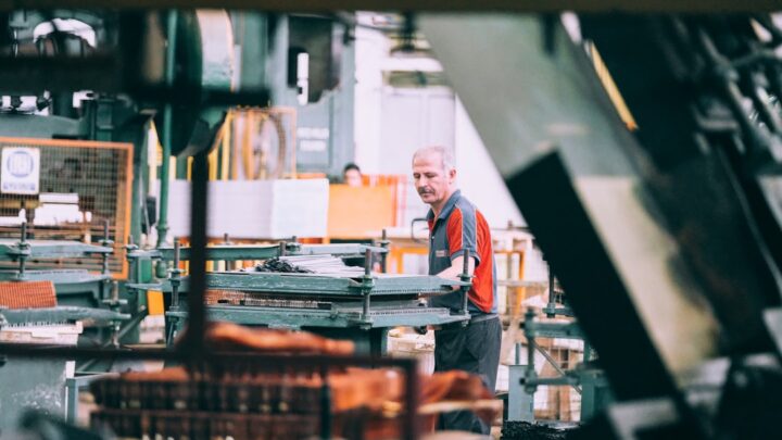 Homem Na Camisa Polo Laranja Em Pe Na Frente Da Mesa bN_aaTKfwM0