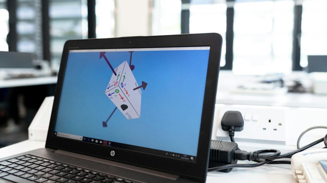 Laptop in an office environment displaying 3D design software on screen, emphasizing technology and creativity.