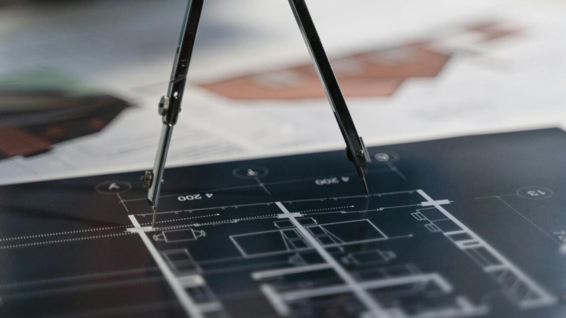 A compass on architectural blueprints, showcasing planning and measurement details.