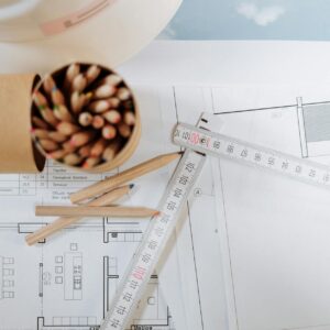 Colorful pencils and ruler atop architectural blueprints on a workspace.