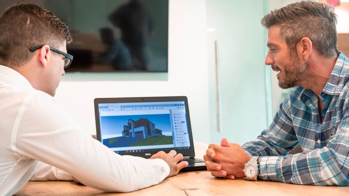 Two professionals discussing a 3D architectural design on a laptop in a modern office.