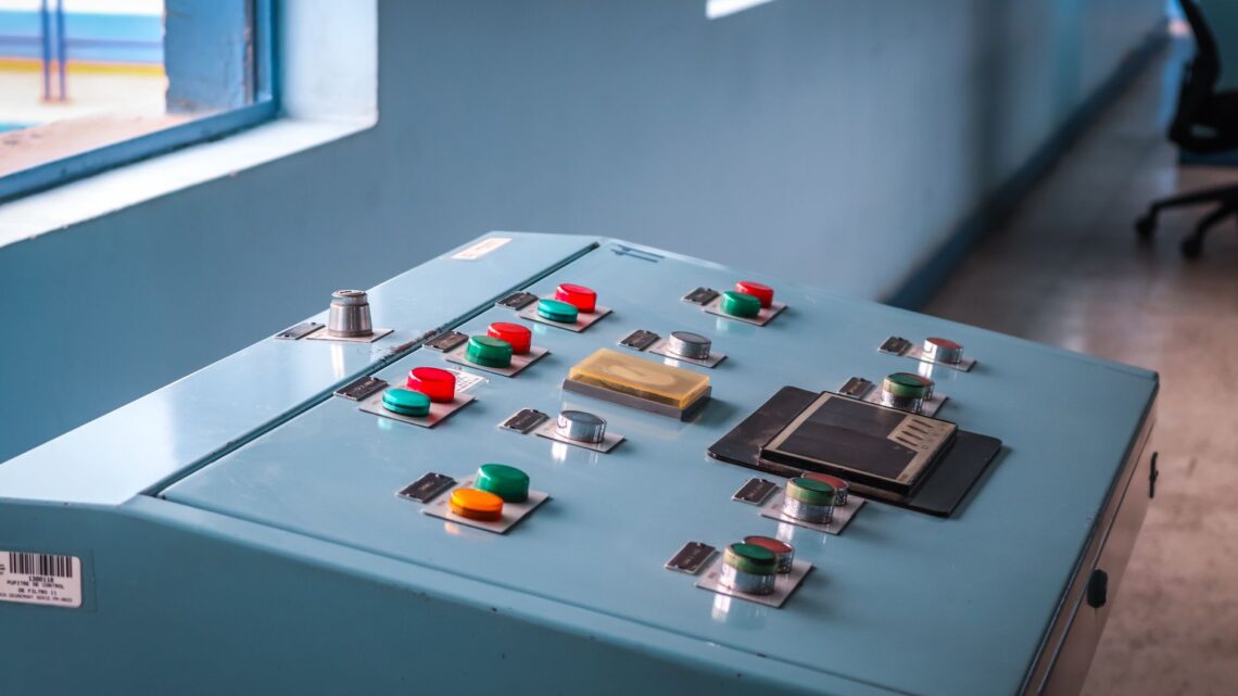 Close-up of an industrial control panel with colorful buttons in a factory setting.