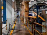 Inside view of an industrial factory featuring conveyor belts and empty walkways.