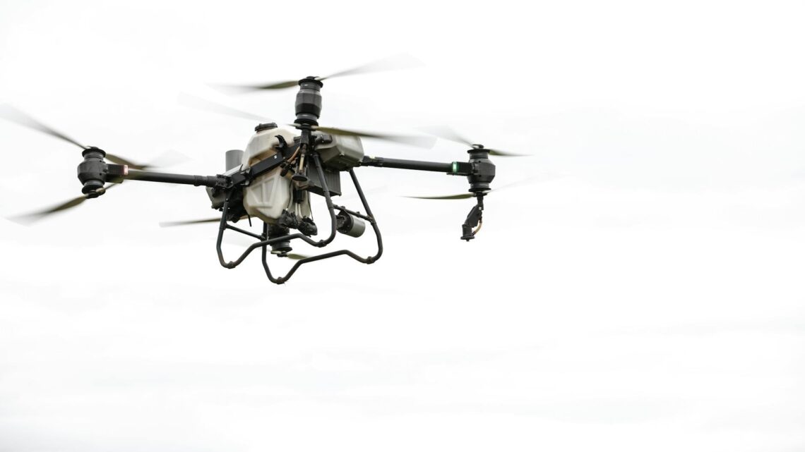 High-tech agricultural drone in flight against a cloudy sky, showcasing modern farming technology.