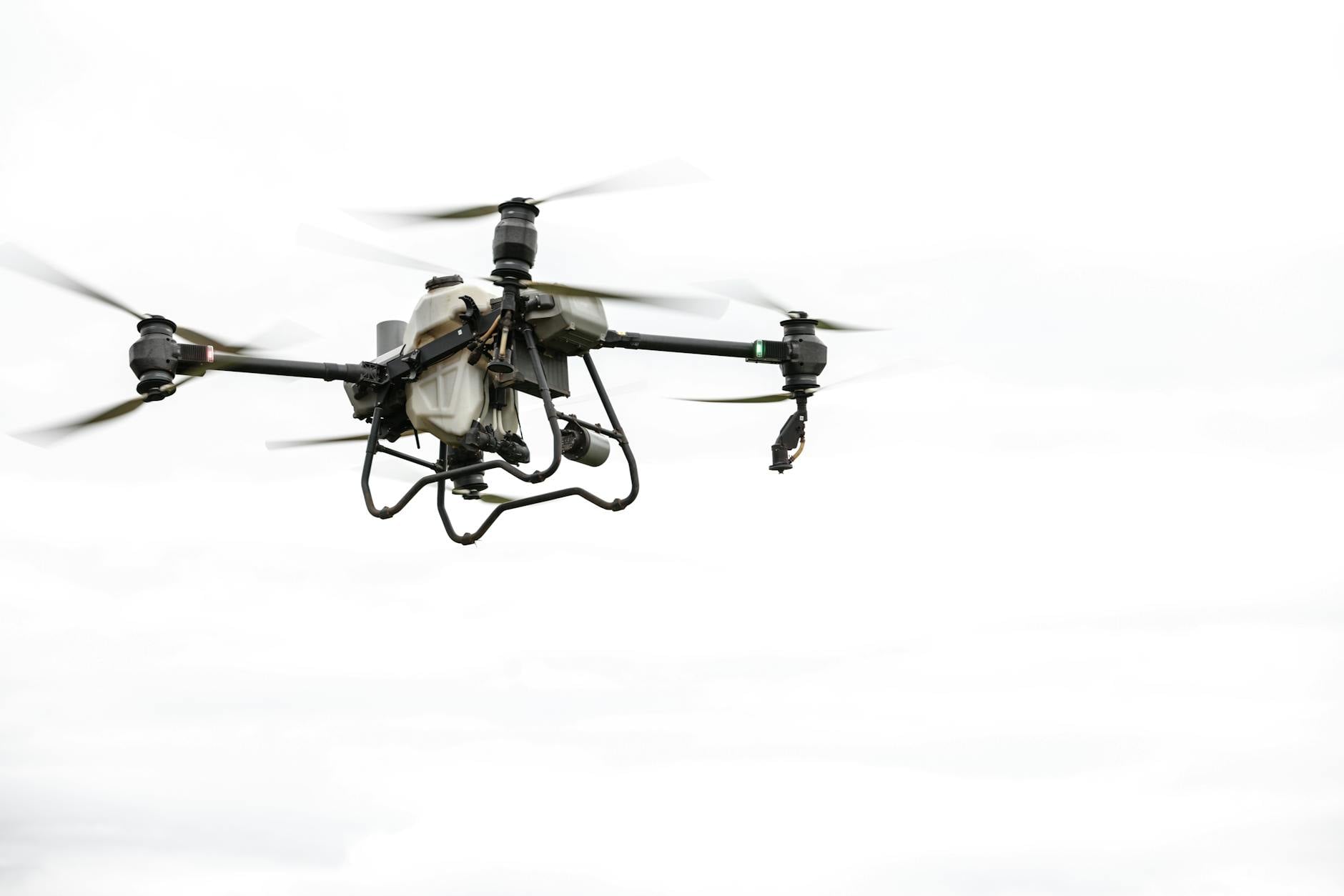 High-tech agricultural drone in flight against a cloudy sky, showcasing modern farming technology.
