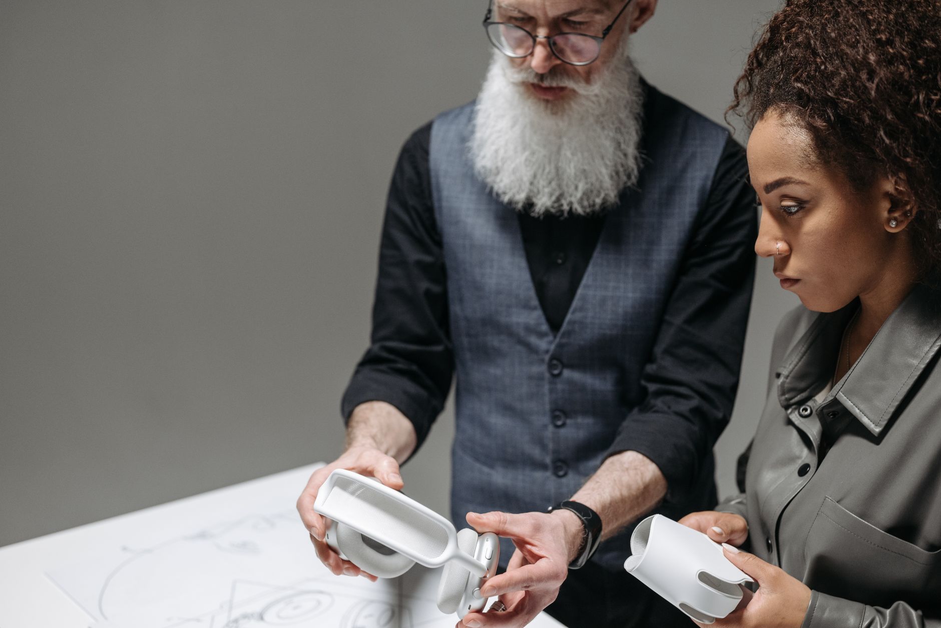 Senior adult and young woman collaborating on headphone design project indoors.