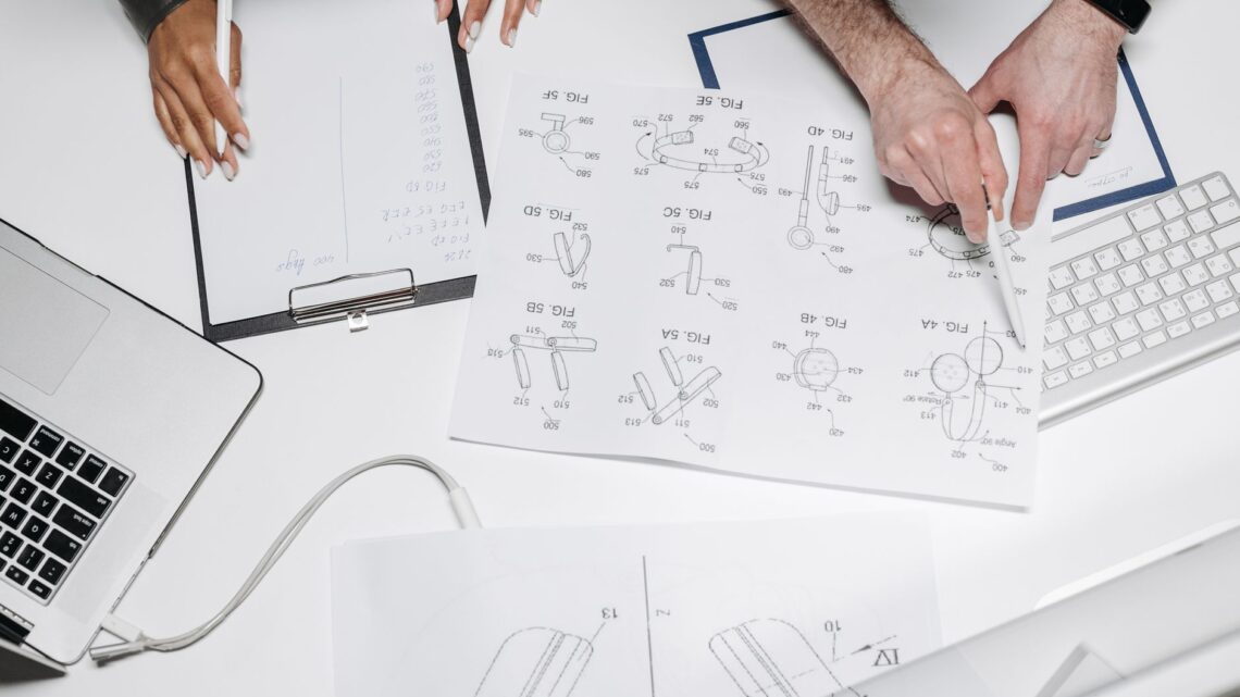 Two professionals collaborate on product design with technical diagrams and notes.
