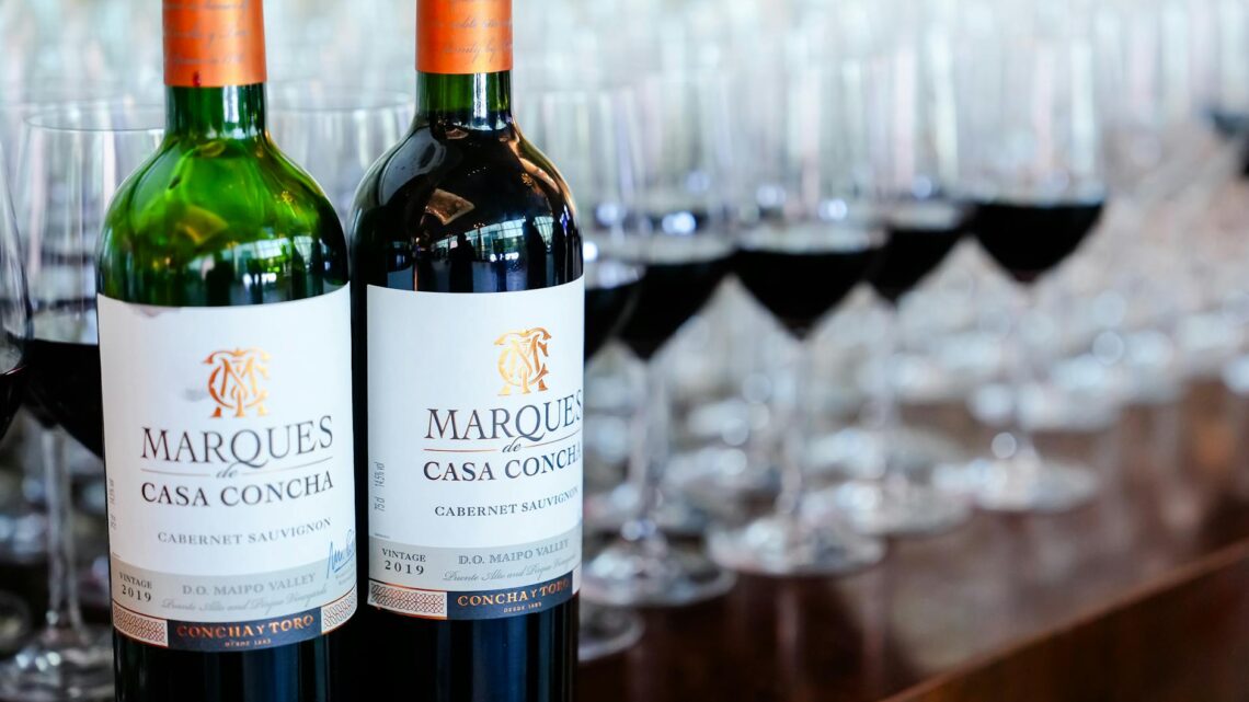Close-up of Marques de Casa Concha wine bottles with filled wineglasses in a table setting.