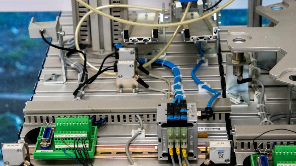 Close-up of industrial equipment showcasing electronic wiring and sensors in a manufacturing setup.