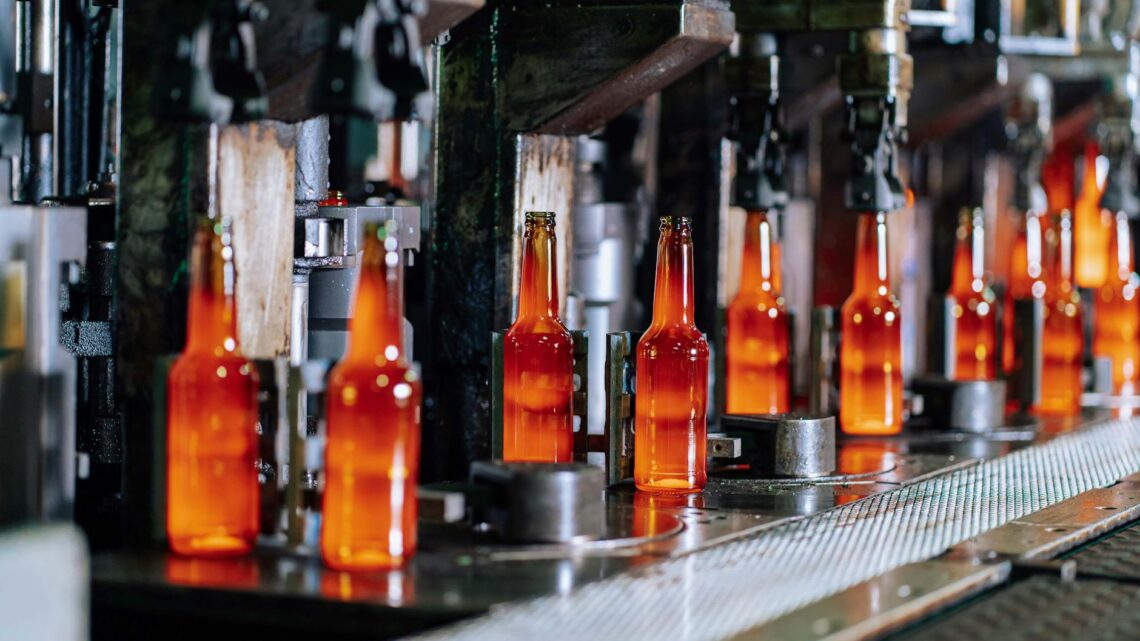 Glass bottles on a production line in a modern glass factory, showcasing industrial automation.