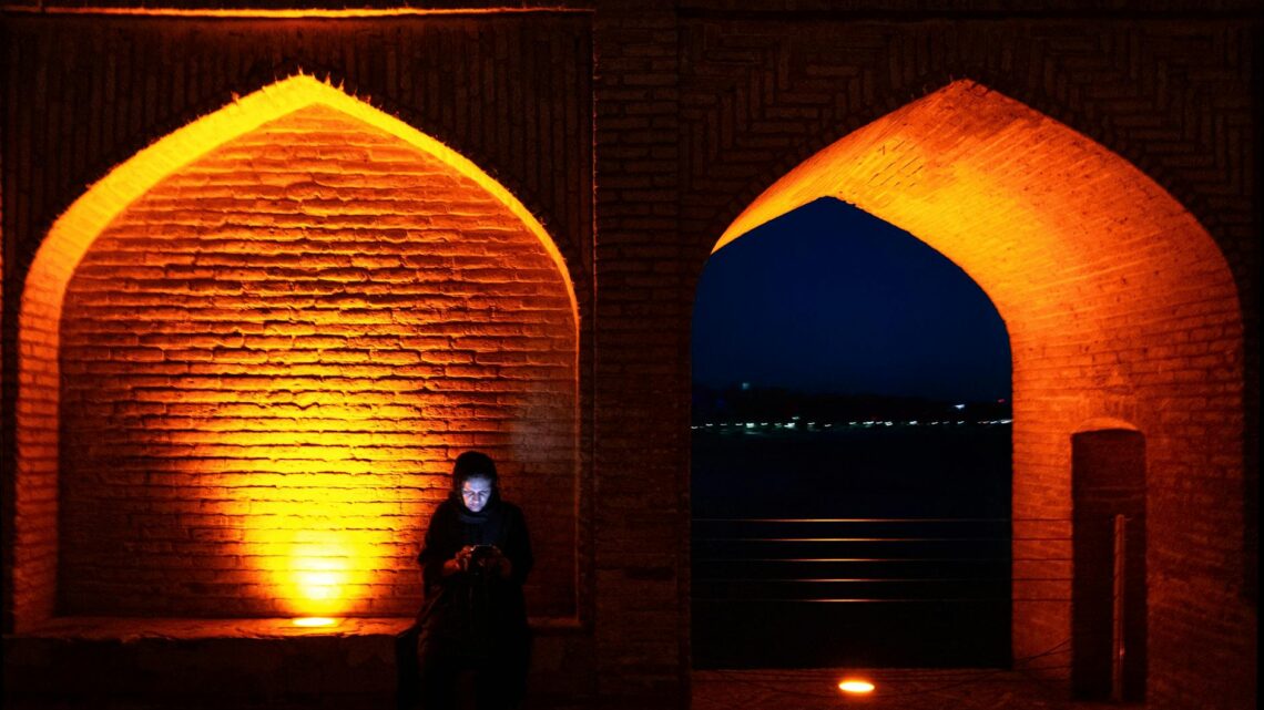 A solitary woman illuminated by city lights at Si-o-se-pol Bridge, Isfahan.