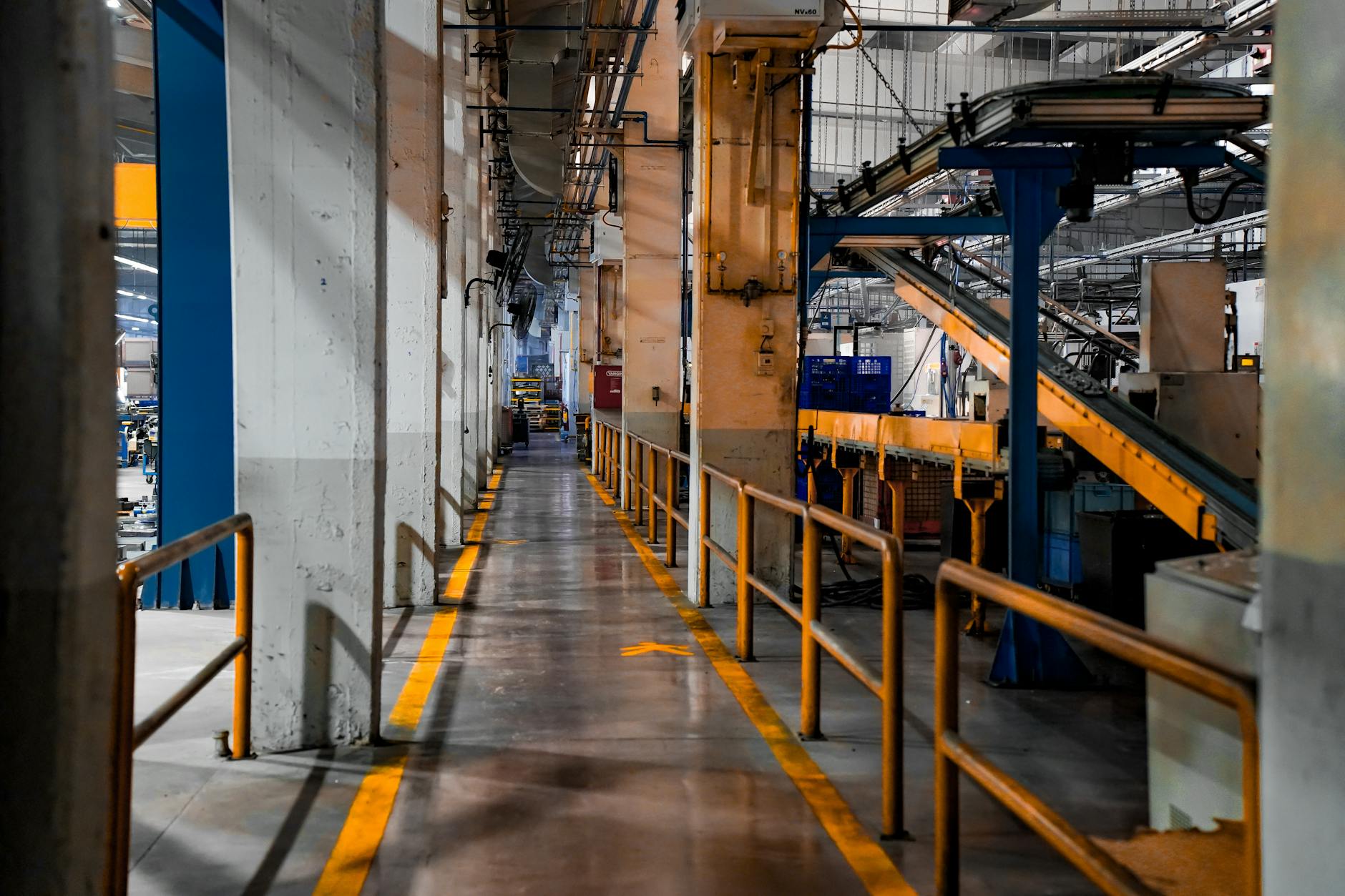 Inside view of an industrial factory featuring conveyor belts and empty walkways.