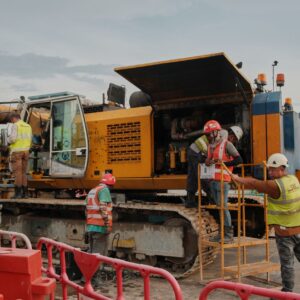 Group of construction workers handling machinery at a worksite with safety gear.