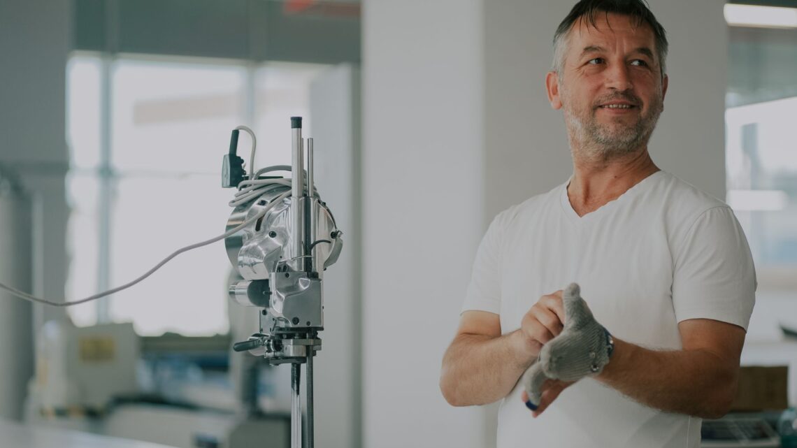 Adult man in an industrial workshop with textile machinery, preparing for work.