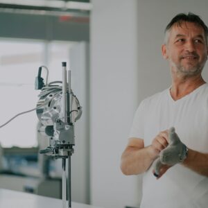 Adult man in an industrial workshop with textile machinery, preparing for work.