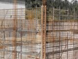 Close-up view of rusting reinforcement steel bars at a construction site with surrounding wooden formwork.