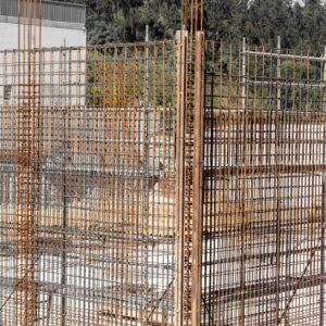 Close-up view of rusting reinforcement steel bars at a construction site with surrounding wooden formwork.