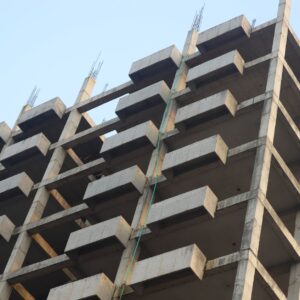 A concrete building skeleton under construction with visible beams and sky backdrop.