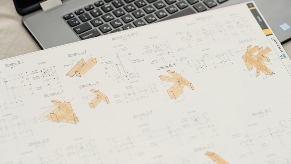 Close-up of architectural blueprints with a laptop on an office desk, showcasing design and planning.