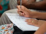 A woman writing in a calendar planner, highlighting organization and time management.