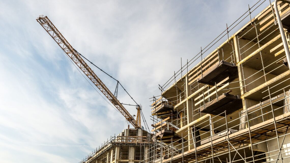 A dynamic view of a construction site with crane and scaffolding on a sunny day.