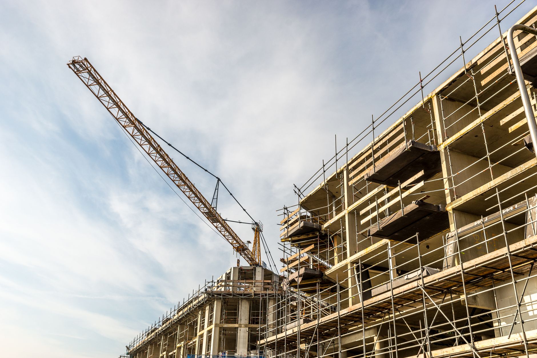 A dynamic view of a construction site with crane and scaffolding on a sunny day.