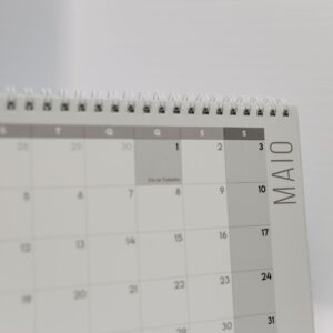 Spiral-bound calendar showing May with focus on weekdays in Portuguese.