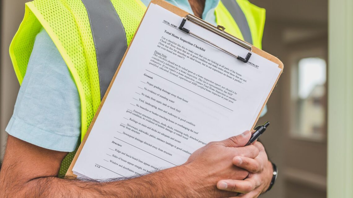 Close-up of home inspector holding a checklist on a clipboard with a pen.