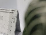 A close-up shot of a desk calendar open on March, with a soft, minimalistic background.