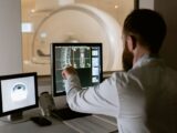 Medical professional reviewing MRI scans on computer screens for diagnostic purposes.