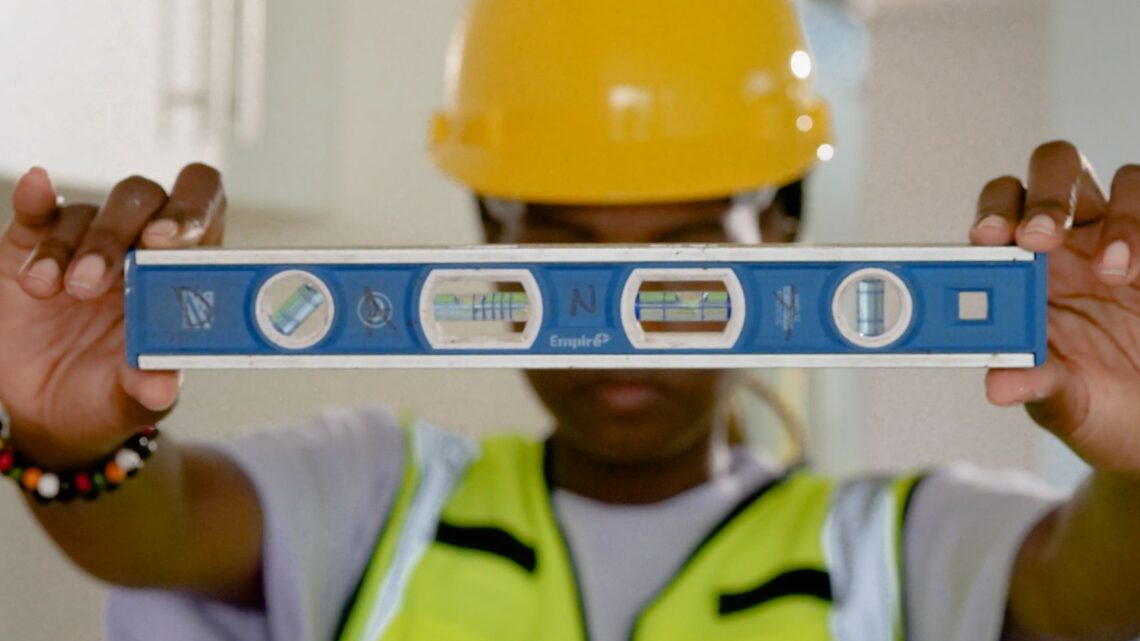Close-up of construction worker holding a spirit level indoors.