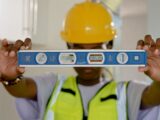 Close-up of construction worker holding a spirit level indoors.