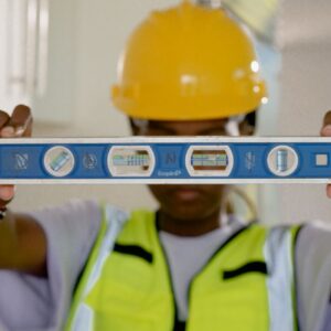 Close-up of construction worker holding a spirit level indoors.