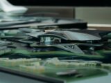 A sleek, futuristic architectural model featuring a metallic design with surrounding green landscape.