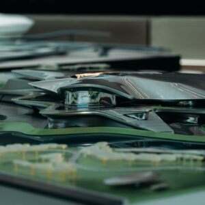 A sleek, futuristic architectural model featuring a metallic design with surrounding green landscape.