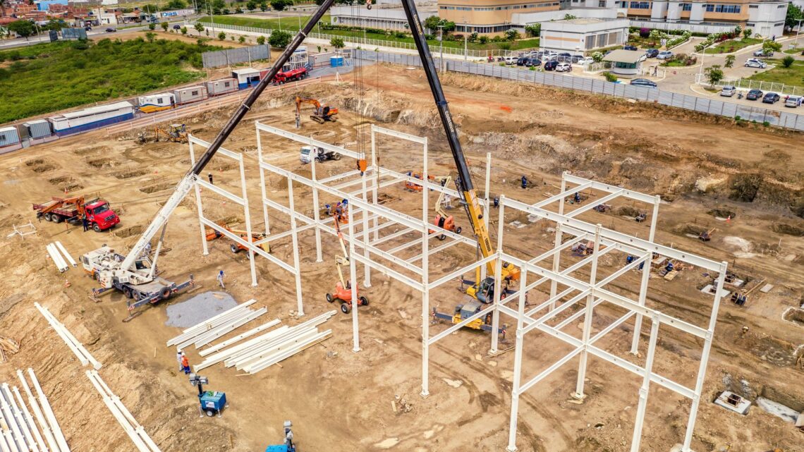 Aerial view of building process rounded with machines and pumpjack near road in town