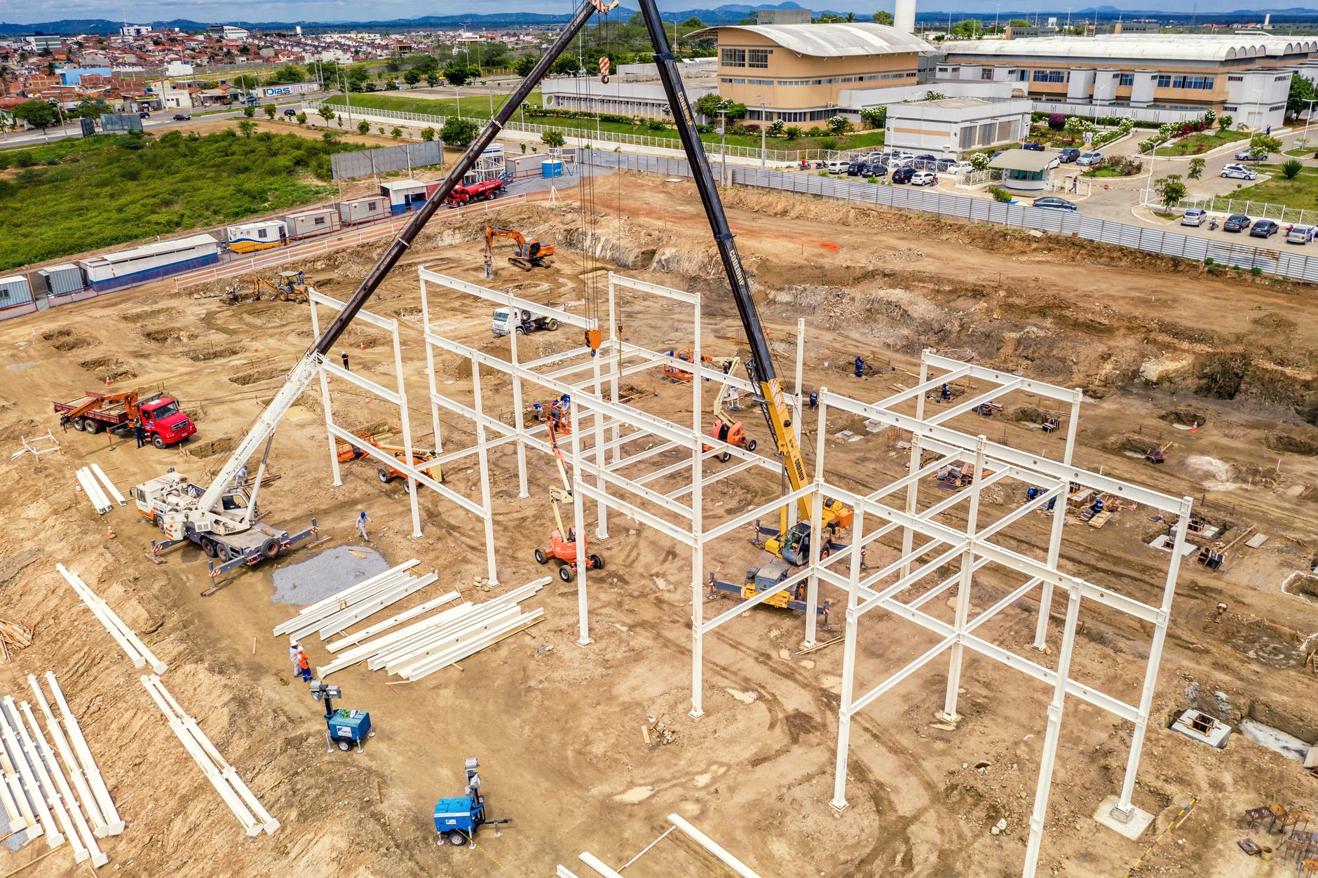 Aerial view of building process rounded with machines and pumpjack near road in town