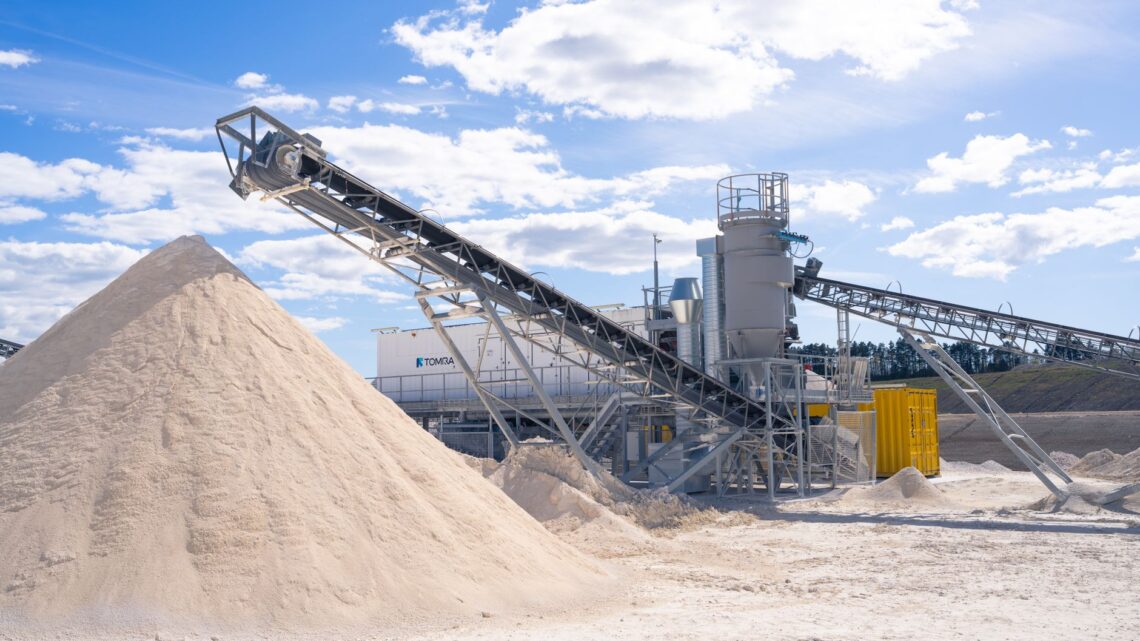 A modern sand processing plant with conveyor belts under a clear blue sky.