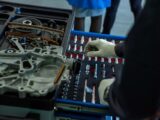 A mechanic in gloves organizing engine parts and tools in a workshop setting.
