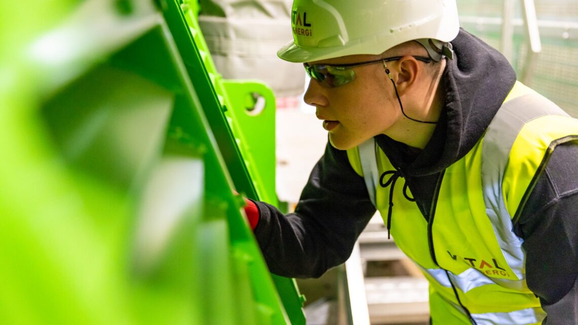 Safety-conscious factory worker inspects machinery for quality control in industrial setting.
