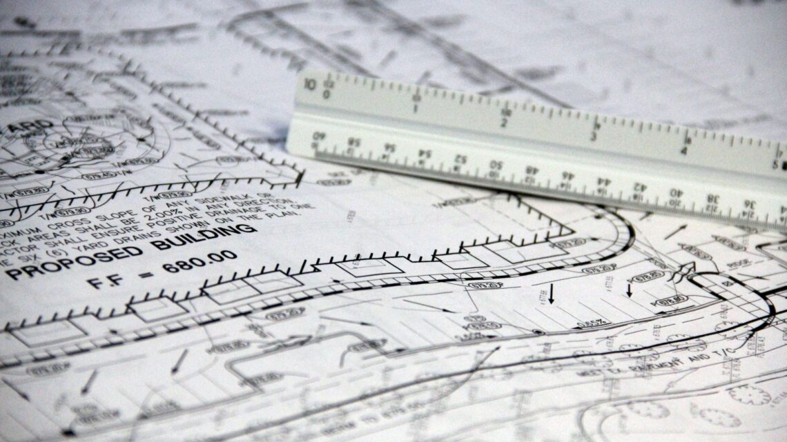 Detailed close-up of architectural blueprints with scale ruler, showing building plans and measurements.