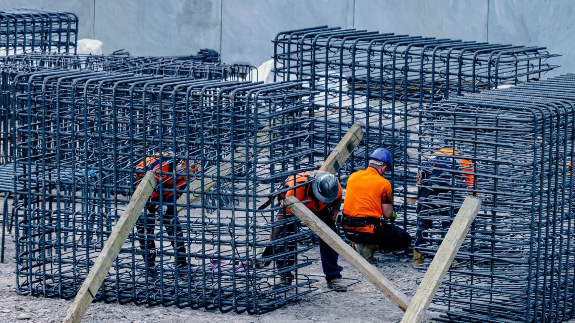 Construction workers assembling steel frames at a site, ensuring structural integrity.