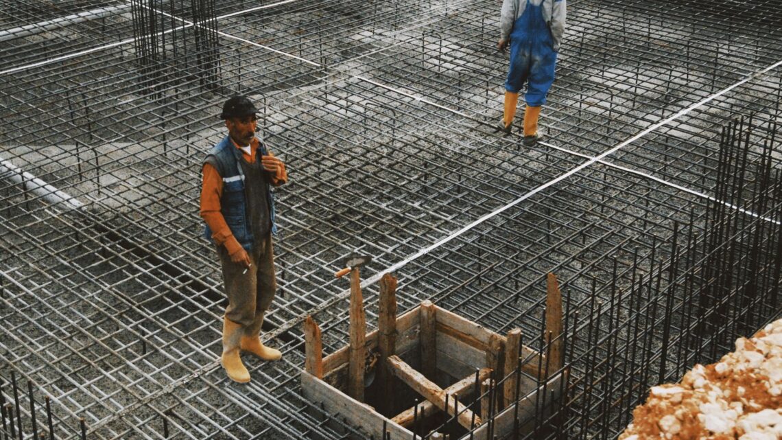 Workers preparing steel reinforcement at a construction site for concrete foundation.