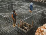 Workers preparing steel reinforcement at a construction site for concrete foundation.