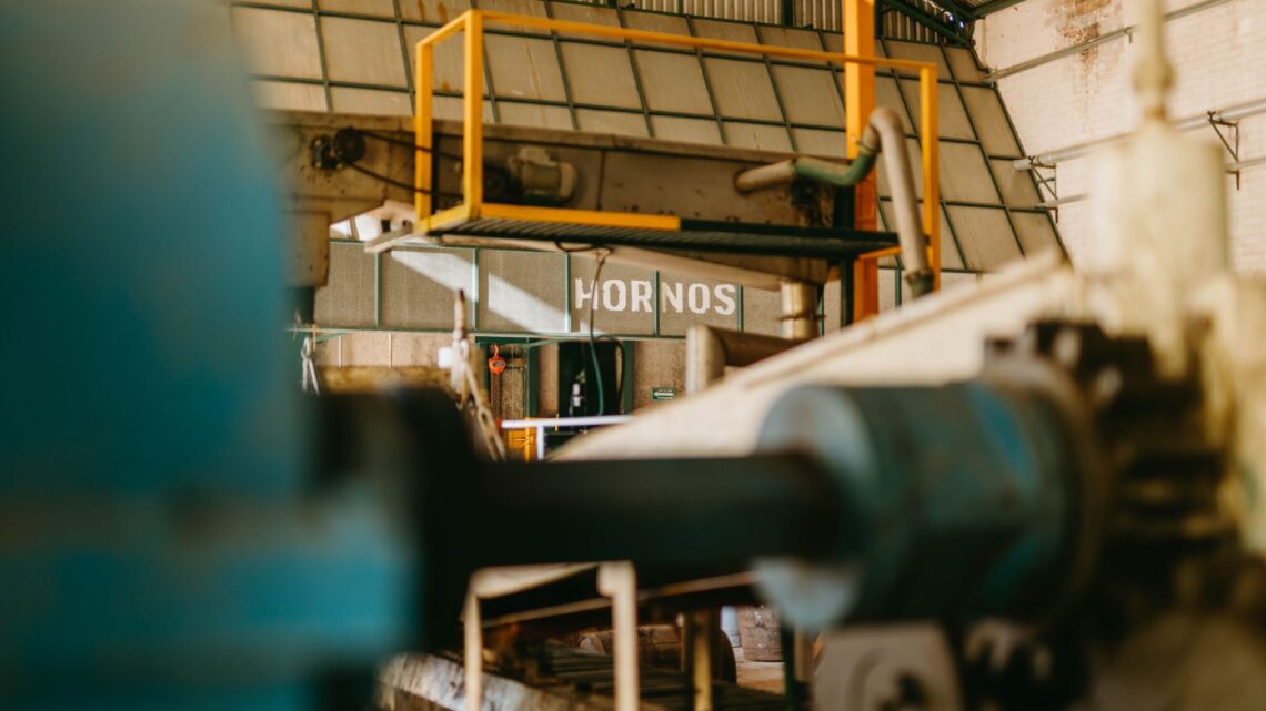 Close-up of heavy machinery inside an industrial factory with focus on ironworks and conveyor systems.