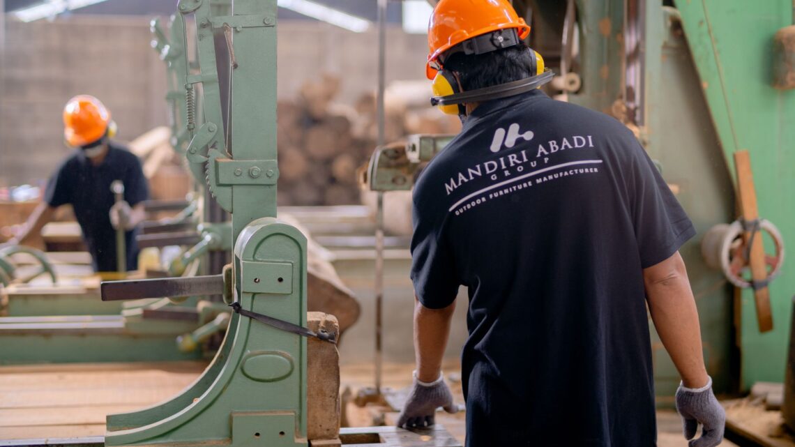Workers wearing protective gear operating machinery in a factory environment, focusing on safety and production.